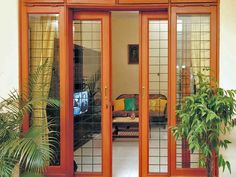 an open patio door leading into a living room with potted plants on the side