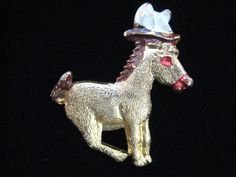 a gold brooch with a horse wearing a hat on it's head and tail