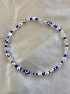 a blue and white beaded bracelet with silver beads on a white sheeted surface