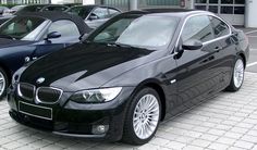 two black cars parked next to each other in a parking lot with white tiles on the ground