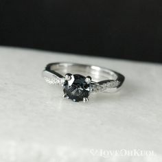 a black and white diamond ring sitting on top of a table