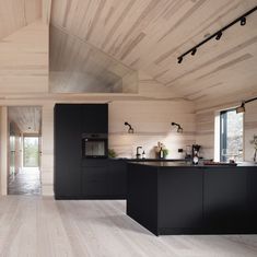 an open kitchen with black cabinets and wood flooring in a modern style house or home