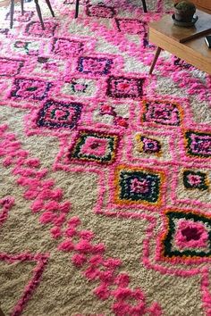 a living room filled with furniture and a pink rug on top of a wooden table