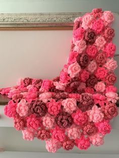 crocheted pink and red flowers hanging from the ceiling in front of a mirror