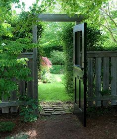 an open gate leading into a lush green yard