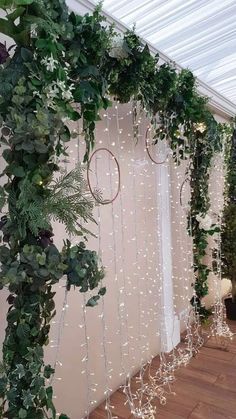 greenery is hanging from the side of a wall with white lights and curtains on it