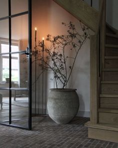 a vase with some flowers in it sitting on the floor next to a stair case