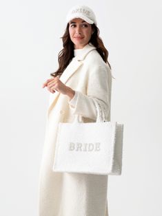 Show off your bridal style as you carry all your honeymoon essentials in Shiraleah's “Bride” Boucle Tote. Made from trendy white boucle fabric, this stylish and roomy tote features the word “Bride” embroidered in faux pearls and rhinestones. Take it with you on your bachelorette trip or anywhere you want to celebrate your big day. Pair with the matching “Bride” Boucle Ball Cap, or other items from Shiraleah's Hitched collection to complete your look! Shiraleah is a trend-driven lifestyle brand f Honeymoon Essentials, Spa Wraps, Bachelorette Trip, Accessories Display, Boucle Fabric, Stylish Hats, Framed Gifts, Frame Decor, Pouch Bag