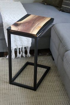 a wooden table sitting on top of a carpeted floor next to a gray couch