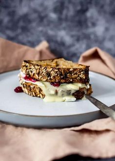 a white plate topped with a sandwich on top of a table next to a fork