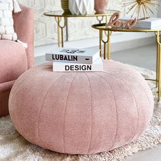 a pink ottoman sitting on top of a white rug next to a gold coffee table