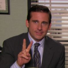 a man in a suit and tie sitting at a desk with a cup of coffee