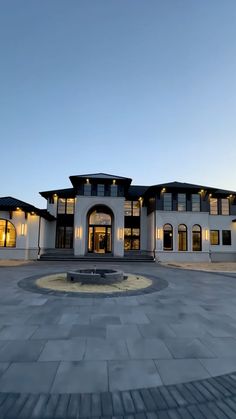 a large white house sitting on top of a cement floor next to a fountain in front of it