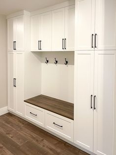 an empty room with white cabinets and wood flooring on one side, black handles on the other