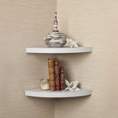 two white shelves with books on them against a beige wallpapered background in a corner