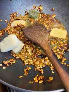 a wooden spoon in a frying pan filled with granola and other food items