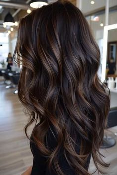 Long, wavy brown hair with caramel highlights in a modern salon setting. Warm Dark Brown Hair With Highlights, Chocolate Highlights On Black Hair, Highlights For Dark Brown Hair Straight, Black Hair With Chocolate Highlights, Dark Brown Lowlights Brunettes, Soft Highlights For Dark Hair, Mocha Highlights On Dark Hair, Hair Color Ideas For Brown Skin Tone, Espresso Balayage