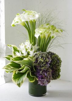 a green vase filled with white and purple flowers