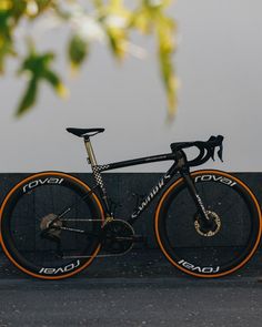 a black and orange bike parked next to a wall