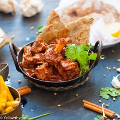 a bowl filled with meat and vegetables next to other food items on a blue surface