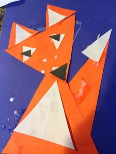 an orange and white paper cut out to look like a fox on a blue background