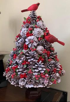 a christmas tree made out of pine cones and red cardinals on top of it