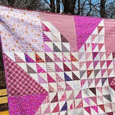 a pink and white quilt hanging from a wooden fence