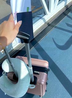 a hand holding a piece of luggage in front of a window