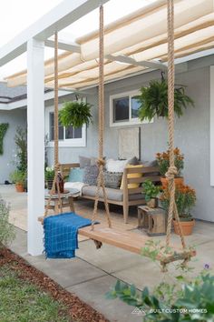 a porch with a swing and potted plants on the back deck, as well as an awning