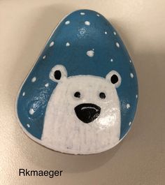 a painted rock with a polar bear on it's face and snow flakes