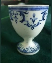 a small blue and white cup sitting on top of a green cloth covered tablecloth