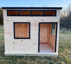 a small house made out of wood with windows on the side and two doors open