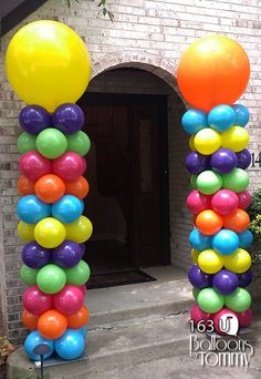 an arch made out of balloons in front of a brick building