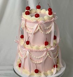 a three tiered cake with cherries and ribbons on it's sides is shown