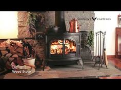 a wood stove sitting inside of a living room next to a pile of firewood