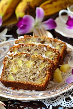 two slices of banana bread sitting on top of a white plate next to purple flowers