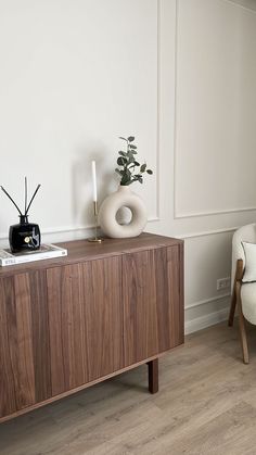 a living room with a wooden cabinet and white chair next to the tv on top of it