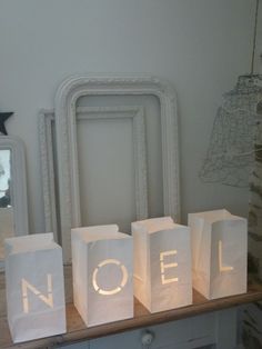 small white bags with the word noel on them sitting on a table in front of a christmas tree