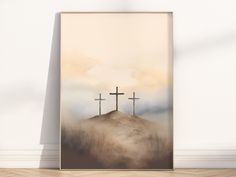 three crosses on top of a hill with fog in the air behind them, framed in a wooden frame