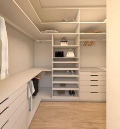 an empty walk - in closet with white cabinets and shoes on the shelves, along with hanging bags