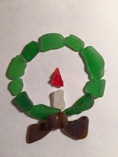 a bracelet made out of green sea glass with a small red triangle on the end