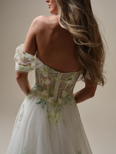 the back of a woman's dress with flowers on it, and her hair blowing in the wind