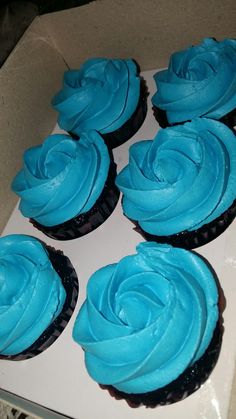 six cupcakes with blue frosting in a box