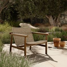 a wooden chair sitting on top of a cement floor next to a potted plant