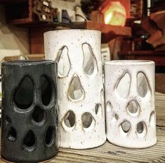 three white and black vases sitting on top of a wooden table