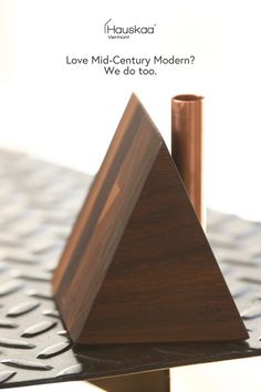 a triangle shaped object sitting on top of a metal surface with the words love mid - century modern? we do too