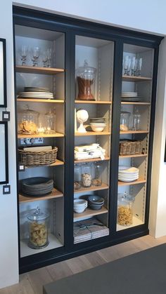 an open glass door cabinet with dishes and bowls in the bottom shelf on each side