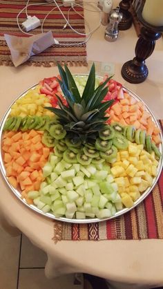 a platter filled with sliced up fruit on top of a table next to a candle