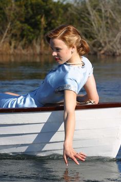 a woman in a blue dress is sitting on a white boat