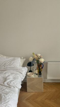 a white bed sitting next to a wooden floor in a bedroom on top of a hard wood floor